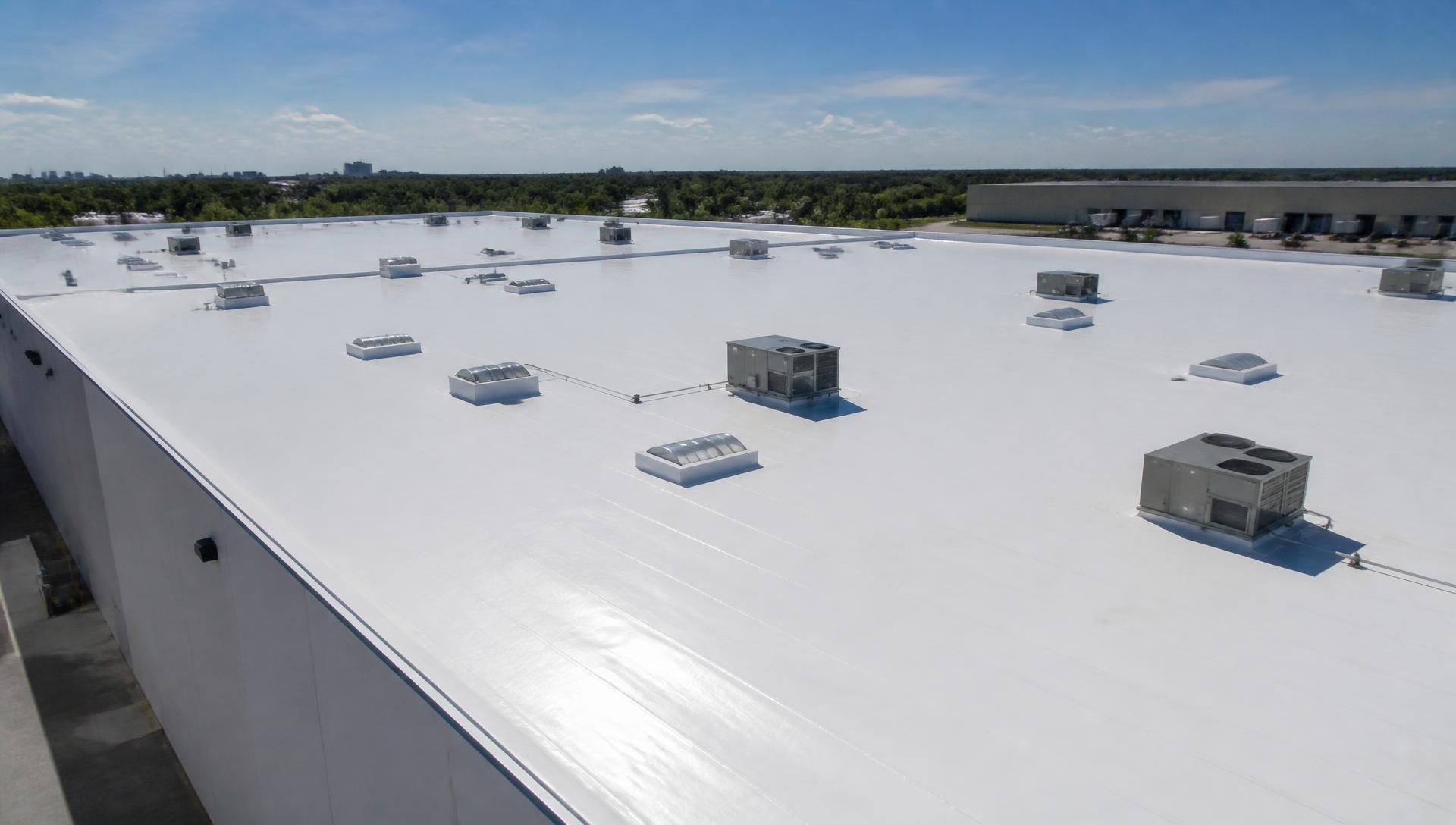 Commercial low-slope roof with a white nano-ceramic cool roof coating in bright sun